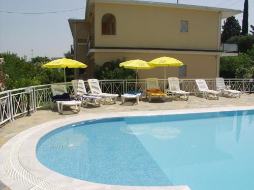 a swimming pool with chairs and umbrellas next to a house at Dimitra Apartments G in Gouvia