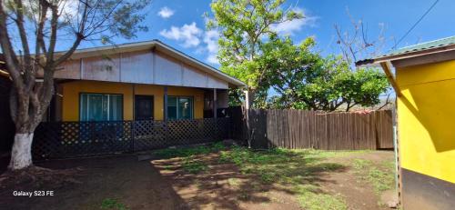 a yellow house with a fence in a yard at Cabañas puna poho in Hanga Roa
