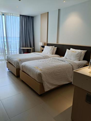 a bedroom with two beds with white sheets and pillows at The Arena Sunrise Cam Ranh in Thôn Hòa Ða