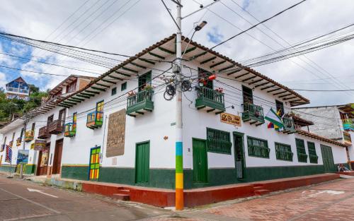 a white building with green doors and windows at HOTEL LA CASONA SAN AGUSTIn in San Agustín