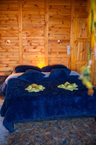 a bedroom with a bed with a blue comforter at Hotel Cabañas y Glamping Colinas De San Diego in San Agustín