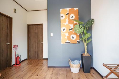 a hallway with a potted plant and a painting on the wall at 逗子海岸近くの広さ104平米の一棟貸しNetflixあり in Hayama