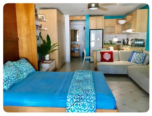 a bedroom with a blue bed and a living room at Cozy Beachfront Studio in San Juan
