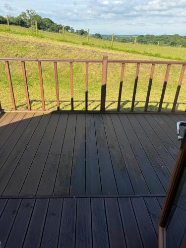 a wooden deck with a fence and a field at Lanercost lodges in Carlisle