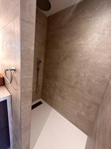 La salle de bains est pourvue d'une douche et d'un mur en carrelage. dans l'établissement Appartement ROSE, Aéroport ST EXUPERY, Groupama stadium, Eurexpo, LDLC Arena, à Pusignan