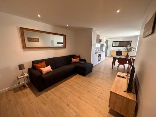 a living room with a black couch and a table at Appartement ROSE, Aéroport ST EXUPERY, Groupama stadium, Eurexpo, LDLC Arena in Pusignan