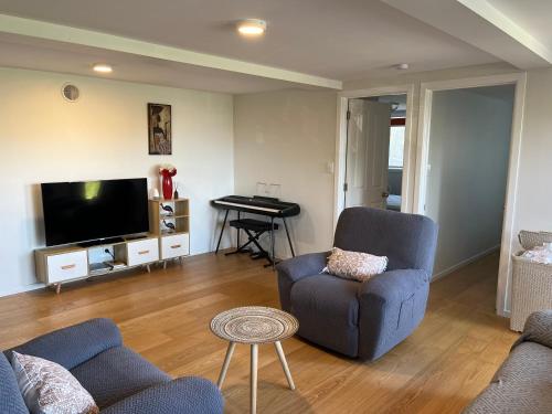 a living room with a couch and a chair and a tv at Peaceful and convenient in Auckland