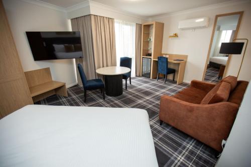 a hotel room with a couch and a table at Dubbo RSL Club Motel in Dubbo