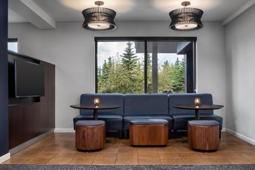 a waiting room with a blue couch and two tables at Courtyard by Marriott Anchorage Airport in Anchorage