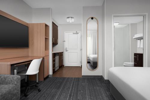 a hotel room with a bed and a desk and a mirror at TownePlace Suites Bridgeport Clarksburg in Bridgeport