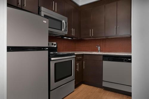 a kitchen with black and white appliances and brown cabinets at TownePlace Suites Bridgeport Clarksburg in Bridgeport