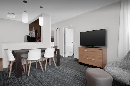 a living room with a dining room table and a television at TownePlace Suites Bridgeport Clarksburg in Bridgeport