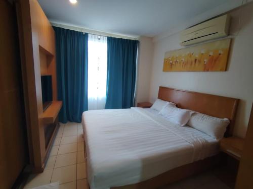a bedroom with a bed and a window with blue curtains at Fratini's Hotel Labuan in Labuan