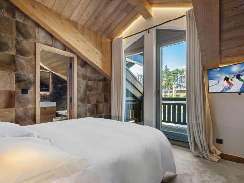 une chambre avec un grand lit et une grande fenêtre dans l'établissement Luxueux Duplex Courchevel 1850, 3 Chambres, près des Pistes, Parking, Services Inclus - FR-1-564-118, à Courchevel
