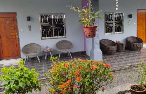 a patio with chairs and plants and flowers at OCEAN LODGE in Pantai Cenang