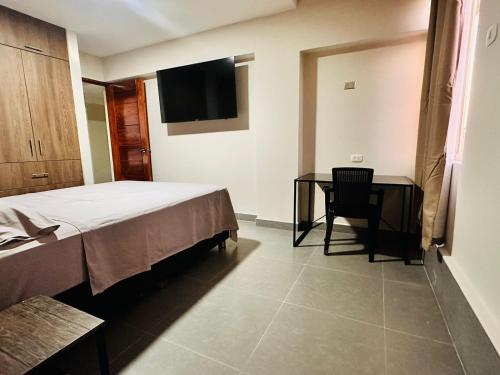 a bedroom with a bed and a desk and a television at Bienvenido a Casa Estancia 3H in Iquitos