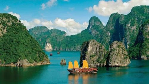 two boats with sails in the water in a bay with mountains at Napoli Hostel Cat Ba in Cat Ba