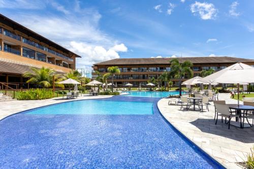 a resort pool with tables and chairs and umbrellas at Eco Resort Praia Dos Carneiros - Vizinho a Igrejinha in Praia dos Carneiros
