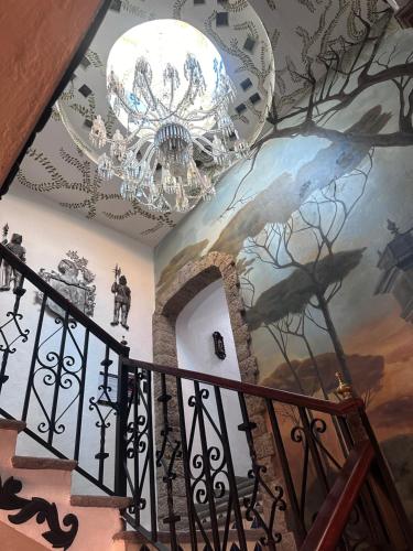 a staircase with a chandelier and a painting on the ceiling at Hotel Boutique La Mansión Guadalajara in Guadalajara