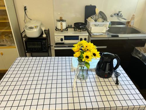 a kitchen with a table with a vase of yellow flowers at 高島市一棟貸切 Biwa Lake琵琶湖 徒歩0分 大人数でご利用だとお得連泊がお得BBQ自転車無料利用可ペット可 in Takashima