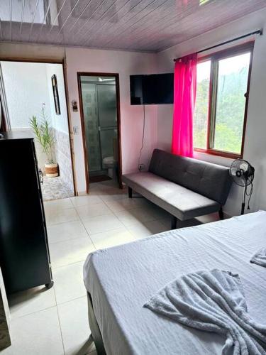 a bedroom with a bed and a couch and a window at Finca Hotel VILLA SOFIA in Montenegro