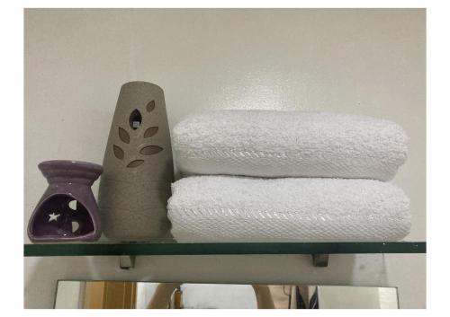 a shelf with towels and a vase and a stack of towels at Bohemian Inspired Studio Unit1 at Trees Residences in Manila