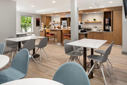 a dining room with tables and chairs and a kitchen at TownePlace Suites Chicago Lombard in Lombard