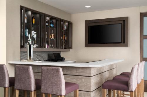a bar in a hotel room with chairs and a tv at Residence Inn by Marriott Milwaukee West in Wauwatosa