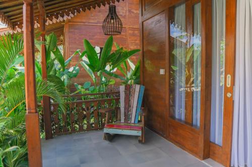 a porch with a wooden door and a chair at Bhalance Retreat in Padangbai