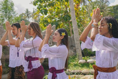 a group of people are performing a pray gesture at Bhalance Retreat in Padangbai
