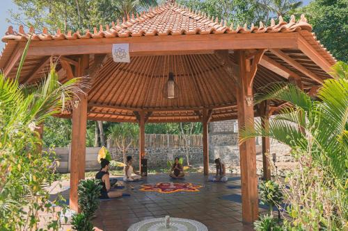 a group of people meditation under a wooden gazebo at Bhalance Retreat in Padangbai
