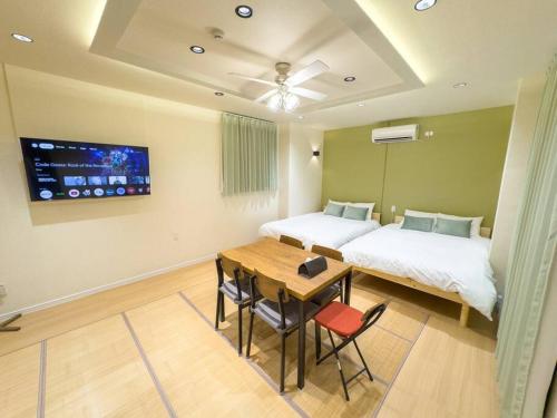 a bedroom with a bed and a table and a bed and a tv at 花宿浅草二番 Hanayado Asakusa2 in Tokyo