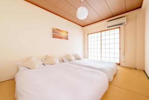 a large white bed in a room with a window at JABA HOUSE Nagaiー11min Nambaー2min Airport line Station in Osaka