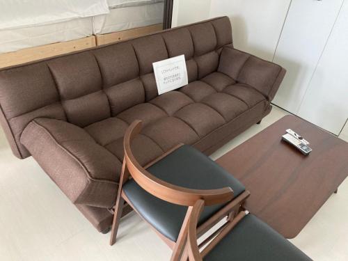a brown couch and a chair in a room at ホテル小樽キャナルビュー AMS海宝樓 in Otaru