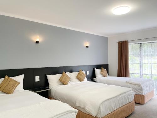 a hotel room with three beds and a window at Golden Chain Country Plaza Motel Halls Gap in Halls Gap