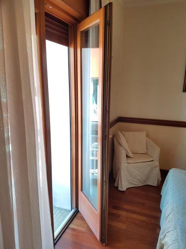 a room with a glass door with a chair and a window at Hotel Minerva in Pordenone