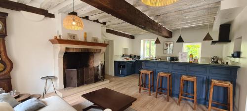 un salon avec une cuisine dotée de placards bleus et d'une cheminée dans l'établissement COTTAGE Les Petites Molières, à Les Essarts-le-Roi