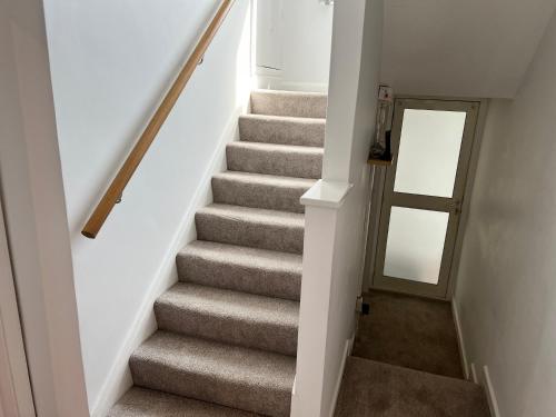 a stairway with a gray carpeted staircase with a mirror at Sennen Cove Cottage in Sennen Cove
