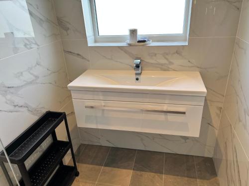 a bathroom with a white sink and a window at Sennen Cove Cottage in Sennen Cove