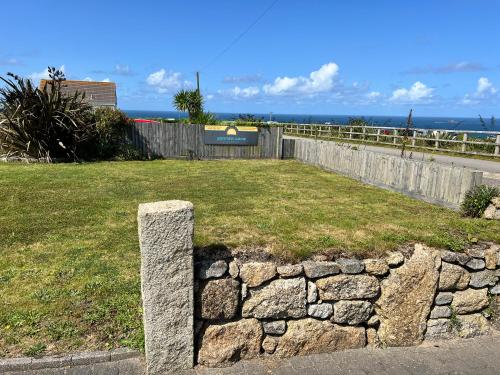 a stone pillar in the grass next to a fence at Sennen Cove Cottage in Sennen Cove