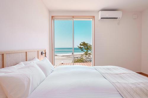 a bedroom with a bed and a view of the beach at VILLA KAWAZU - Umi - in Mitaka