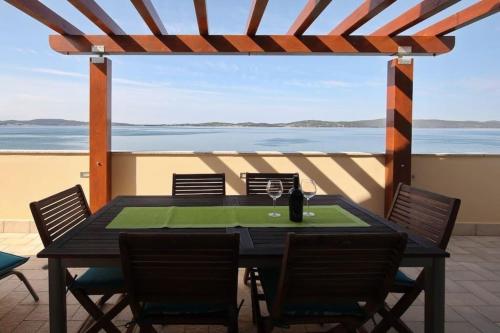 a table and chairs on a patio with a view of the ocean at Penthouse mit Balkon für fünf Personen in Bibinje