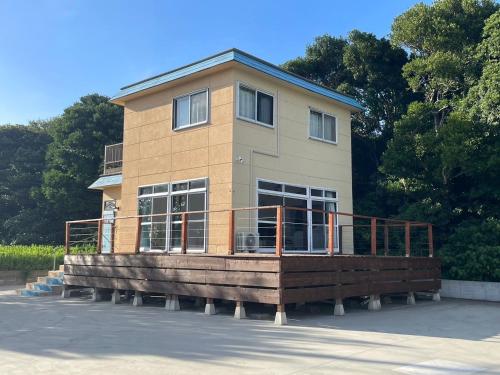 a house with a large wooden deck in a parking lot at Itoshima Beach House in Itoshima