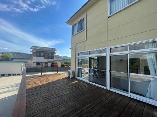 a house with a wooden deck next to a building at Itoshima Beach House in Itoshima