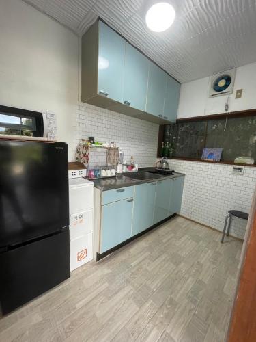 a kitchen with blue cabinets and a black refrigerator at Itoshima Beach House in Itoshima
