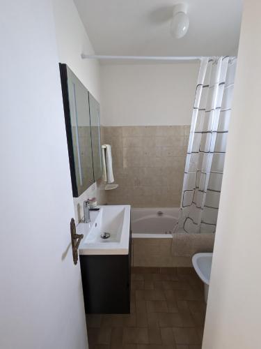 une salle de bain avec un lavabo et une baignoire dans l'établissement Maison de vacances 400 m de la plage et du port de la Turballe, à La Turballe