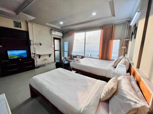 a hotel room with two beds and a flat screen tv at Aizawl Guest House in Āīzawl