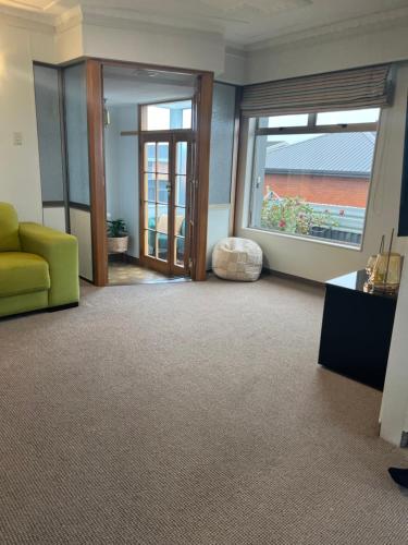 a living room with a yellow couch and windows at Heart of Windsor in Invercargill
