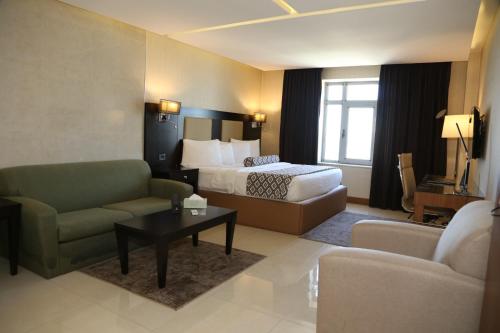 a hotel room with a bed and a couch and a table at Olive Tree Amman in Amman