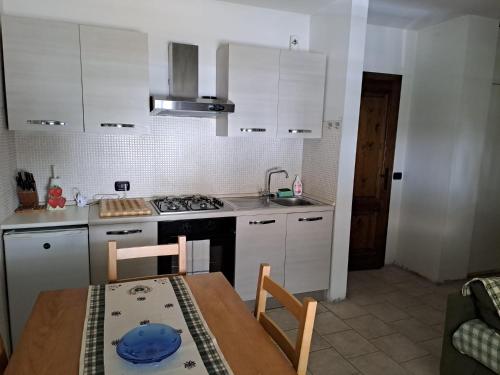 a kitchen with white cabinets and a wooden table with chairs at Dolomiti House in Pinzolo